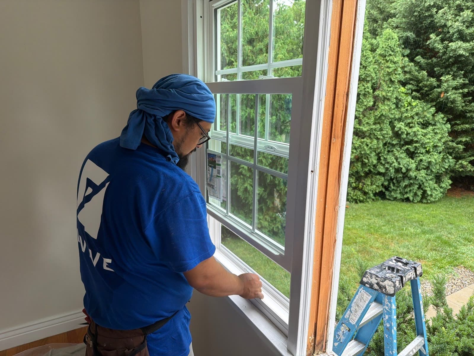 Revive installer in branded gear fitting a new ProVia colonial-grid window in the same room