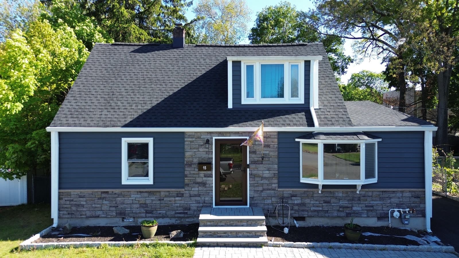 Finished navy lap and board-and-batten siding with stone surround on a New Jersey home