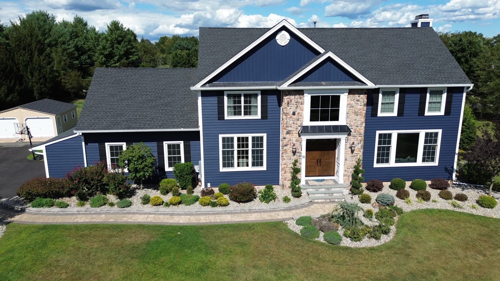 Same New Jersey home after Revive renovation with navy siding, stone surround, and new windows